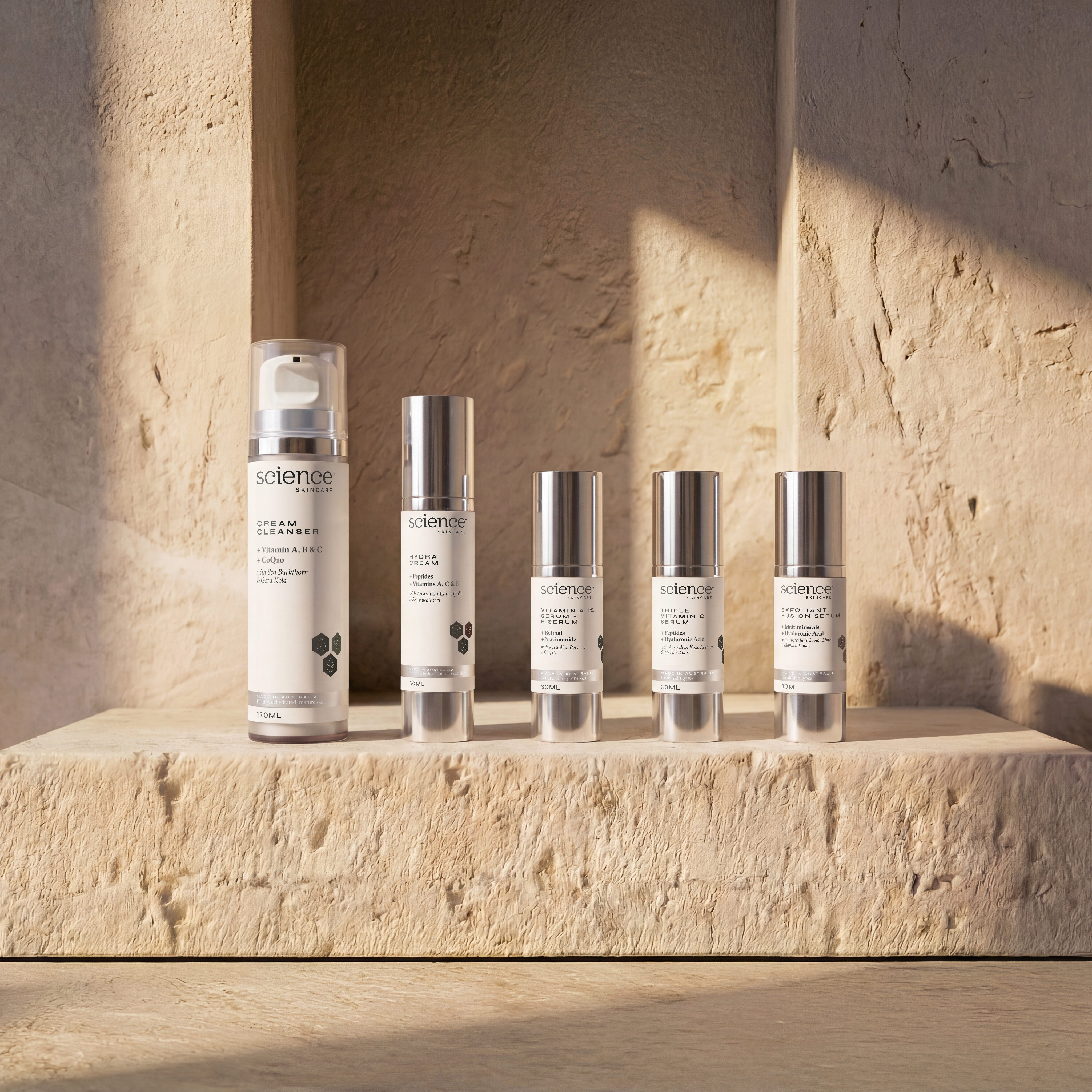 Authentic Ageing Collection lifestyle image showing Cream Cleanser, Hydra Cream, Vitamin A 1% + B Serum, Triple Vitamin C Serum and Exfoliant Fusion Serum by Science Skincare, styled on a warm stone ledge within a sculpted sandstone niche