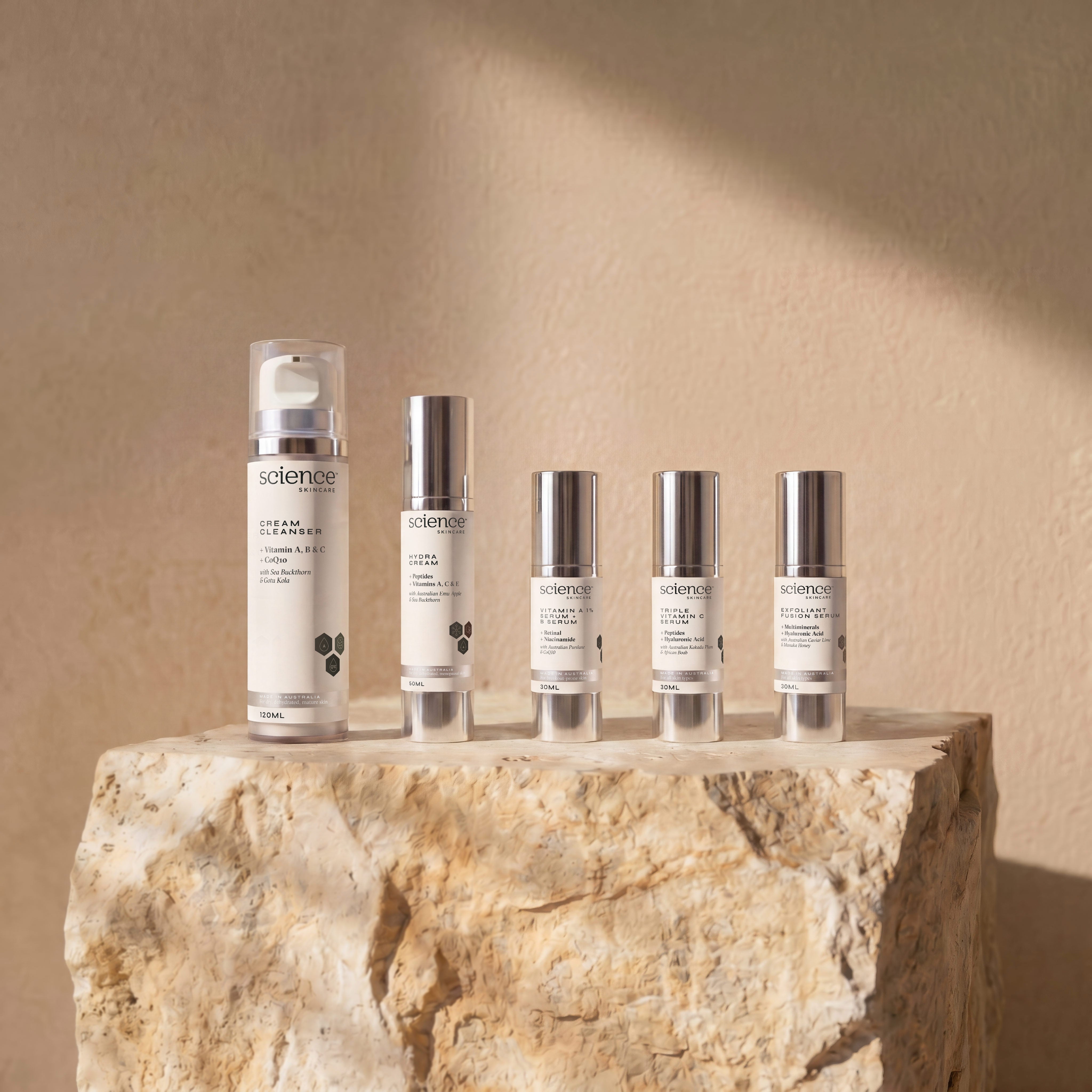 Authentic Ageing Collection lifestyle image showing Cream Cleanser, Hydra Cream, Vitamin A 1% + B Serum, Triple Vitamin C Serum and Exfoliant Fusion Serum by Science Skincare, styled on a raw stone plinth with natural shadow play
