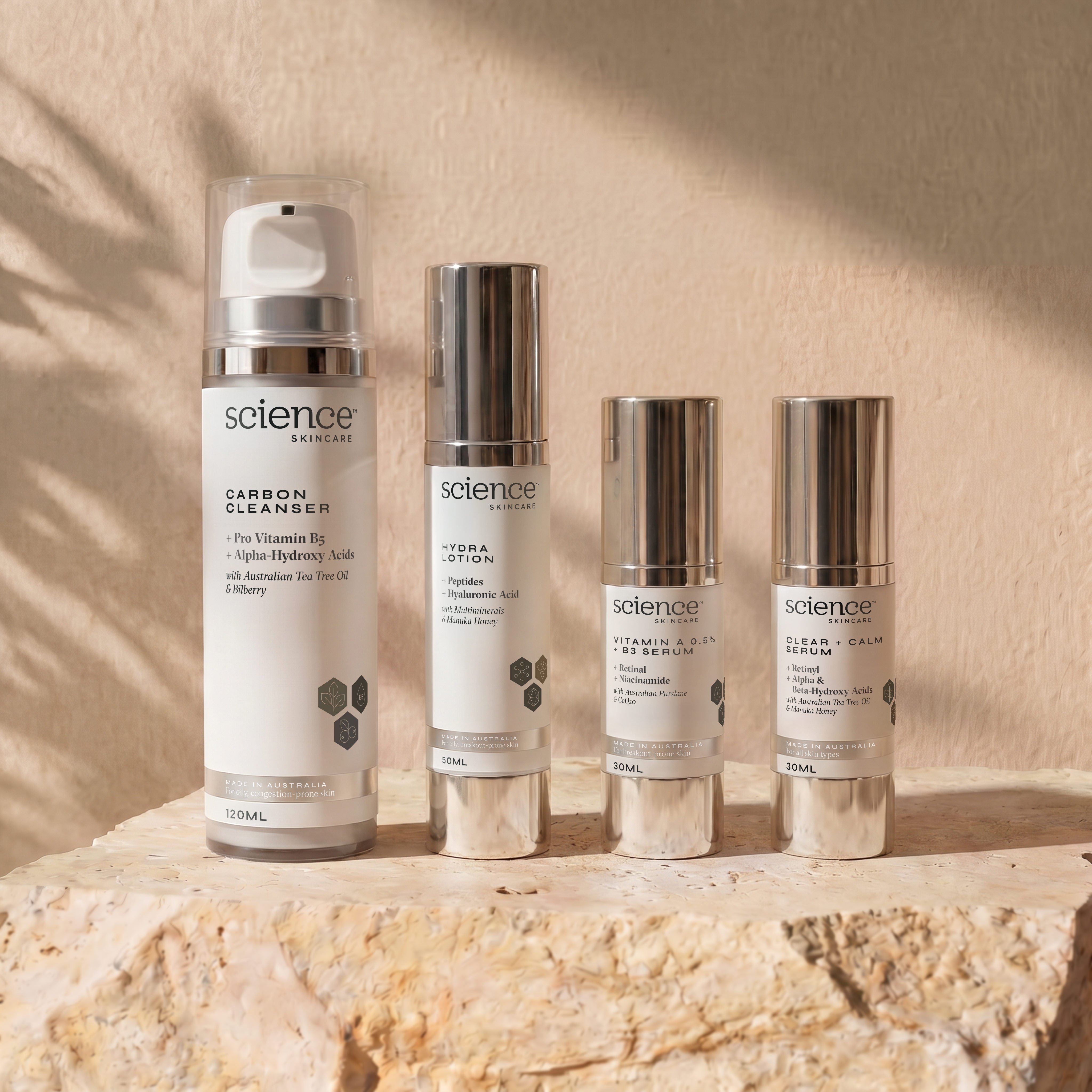 Breakout Collection lifestyle image showing Carbon Cleanser, Hydra Lotion, Vitamin A 0.5% + B3 Serum and Clear + Calm Serum by Science Skincare, styled on a raw stone plinth with natural shadow play