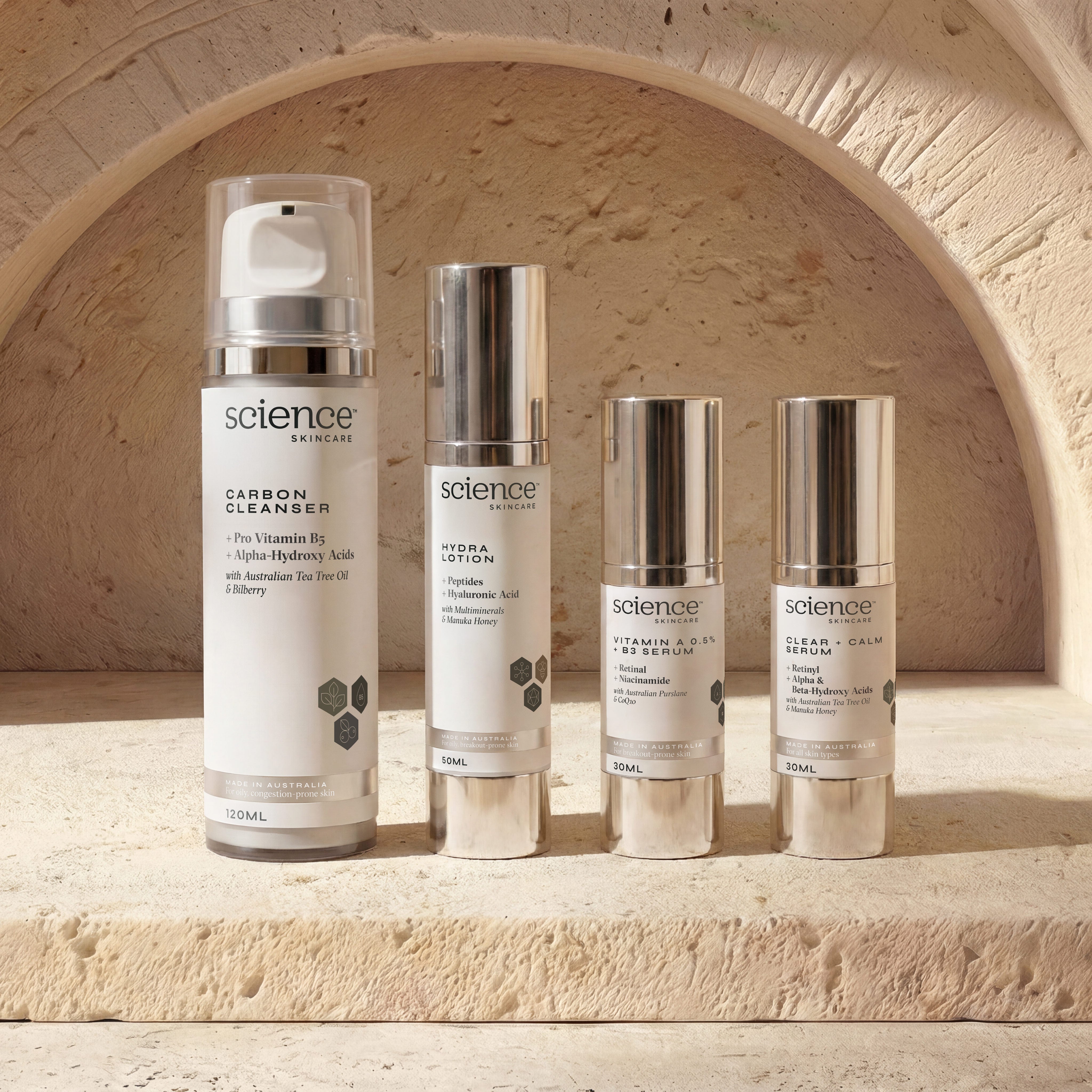 Breakout Collection lifestyle image showing Carbon Cleanser, Hydra Lotion, Vitamin A 0.5% + B3 Serum and Clear + Calm Serum by Science Skincare, styled on a stone ledge against a warm sandstone arch