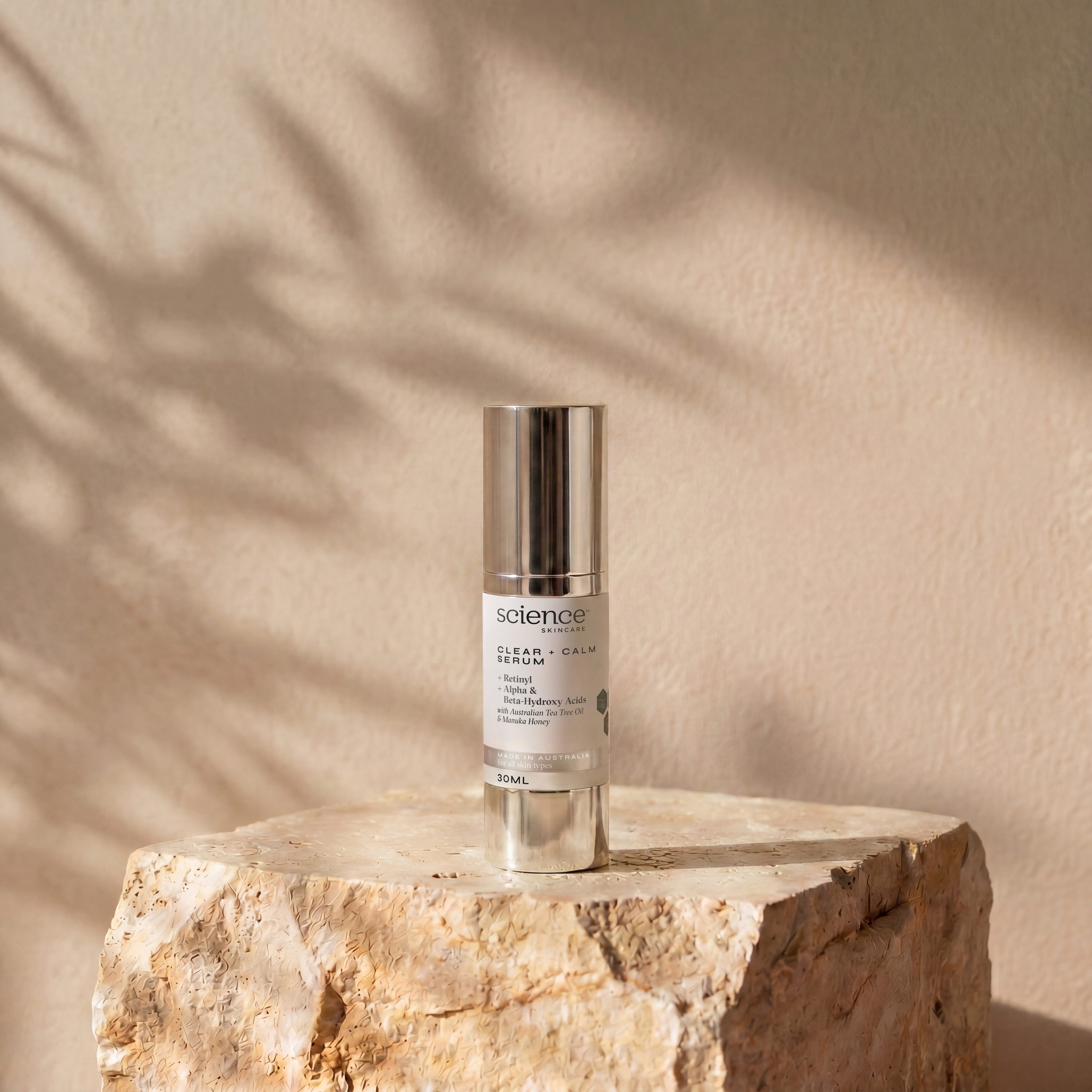 Clear + Calm Serum lifestyle image showing the 30ml Science Skincare serum with retinyl, alpha and beta-hydroxy acids, Australian tea tree oil and manuka honey, styled on a raw stone plinth with natural palm shadow play
