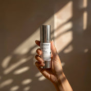 Enlighten Serum lifestyle image showing the 30ml Science Skincare brightening serum with peptides, niacinamide, Song-yi mushroom and licorice, styled on a raw stone plinth with natural shadow play
