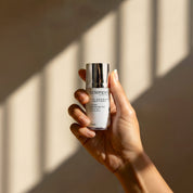 Eye Nourish + Peptides lifestyle image showing a hand holding the 15ml Science Skincare eye treatment with arnica, hyaluronic acid, emu bush and sea buckthorn, against a warm wall with geometric light shadows