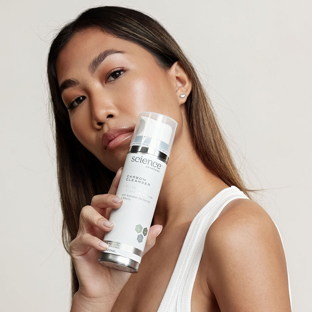 Woman holding a skincare product with a plain background