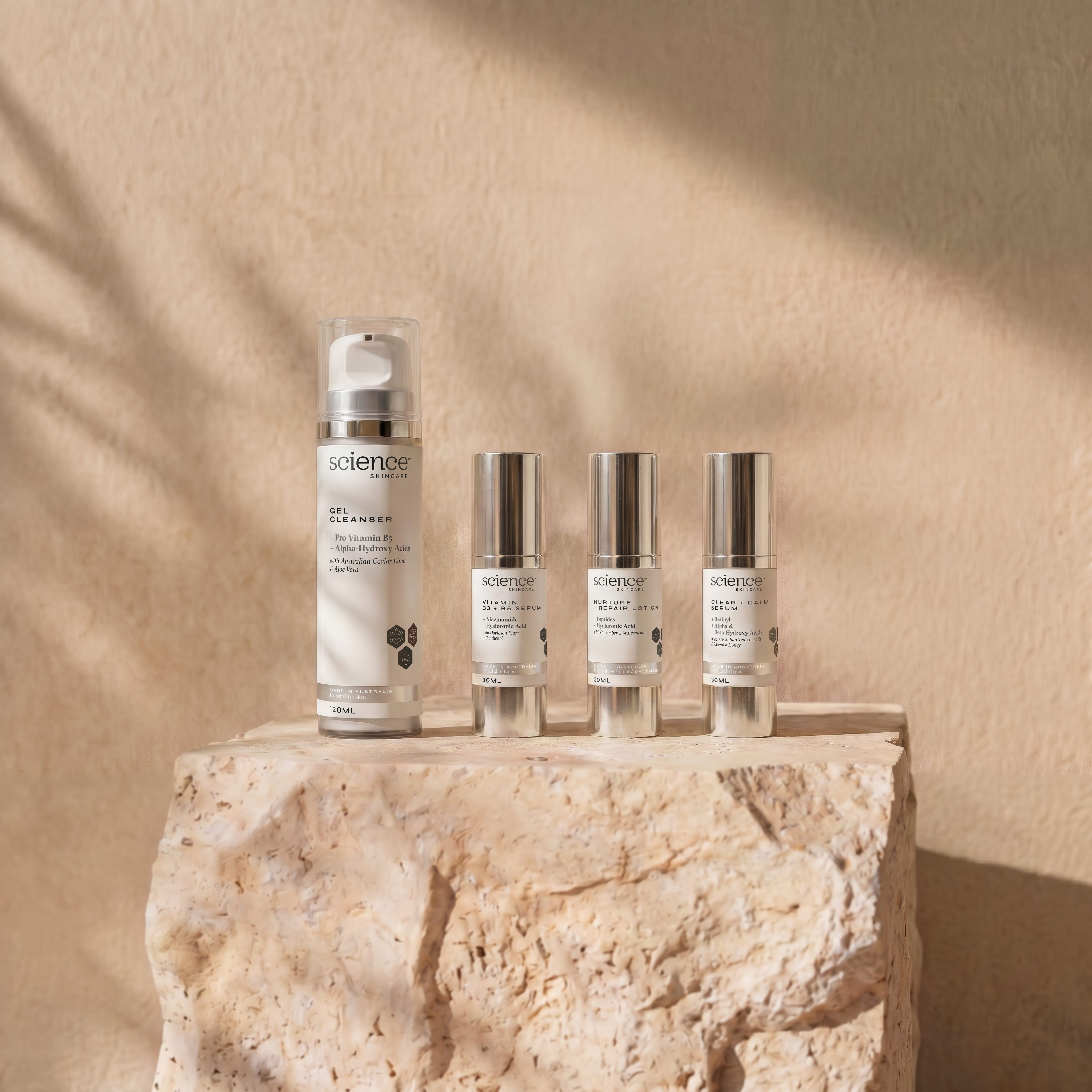 Soothe + Calm Collection lifestyle image showing Gel Cleanser, Vitamin B3 + B5 Serum, Nurture + Repair Lotion and Clear + Calm Serum by Science Skincare, styled on a raw stone plinth with natural shadow play