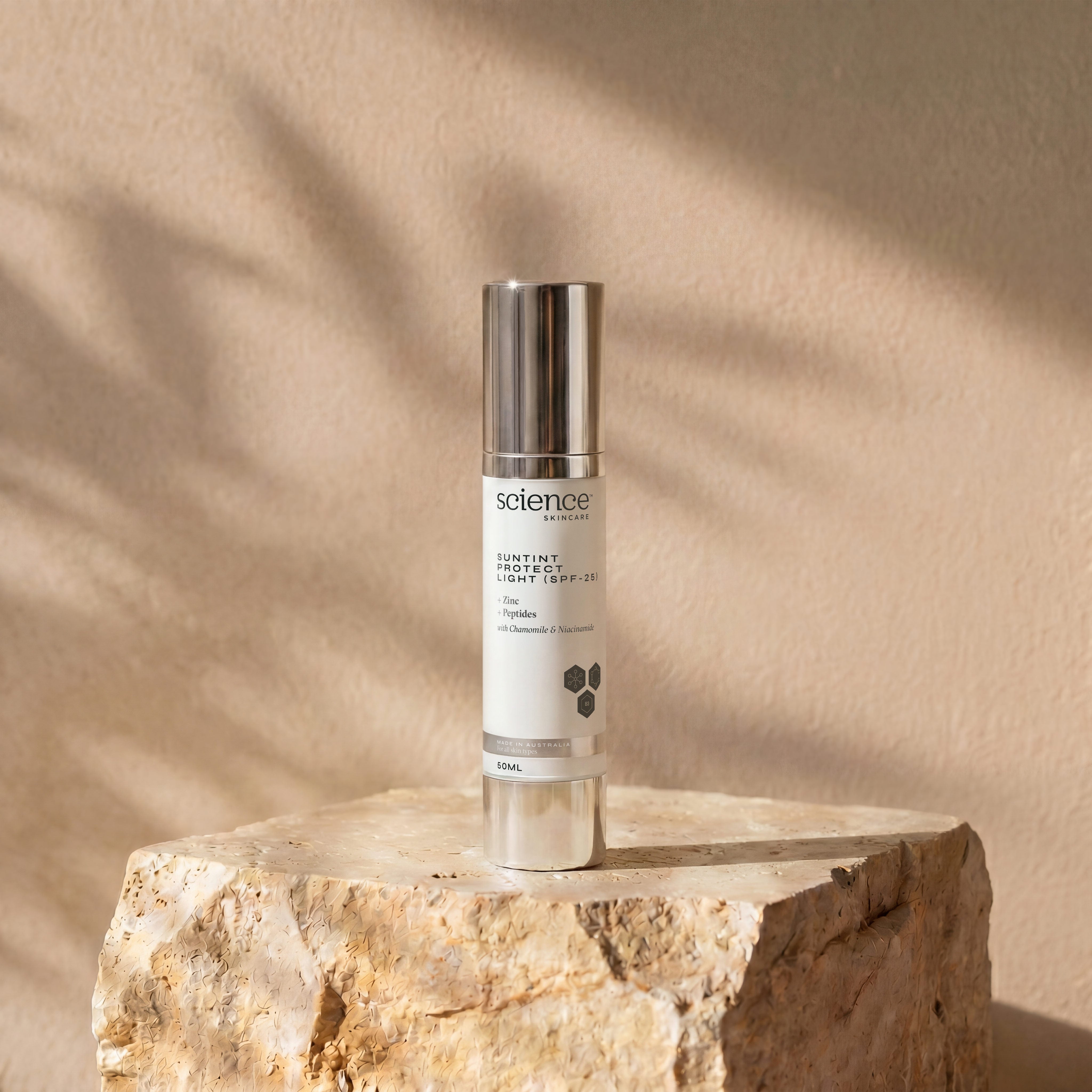 Suntint Protect Light SPF-25 lifestyle image showing the 50ml Science Skincare tinted sunscreen styled on a raw stone plinth with natural shadow play
