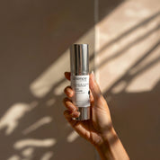 Vitamin A 0.5% + B3 Serum lifestyle image showing a hand holding the 30ml Science Skincare serum with retinal, niacinamide, Australian purslane and CoQ10, against a warm wall with dappled light shadows
