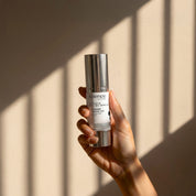 Vitamin B3 + B5 Serum lifestyle image showing a hand holding the 30ml Science Skincare serum with niacinamide, hyaluronic acid, Davidson plum and panthenol, against a warm wall with geometric light shadows
